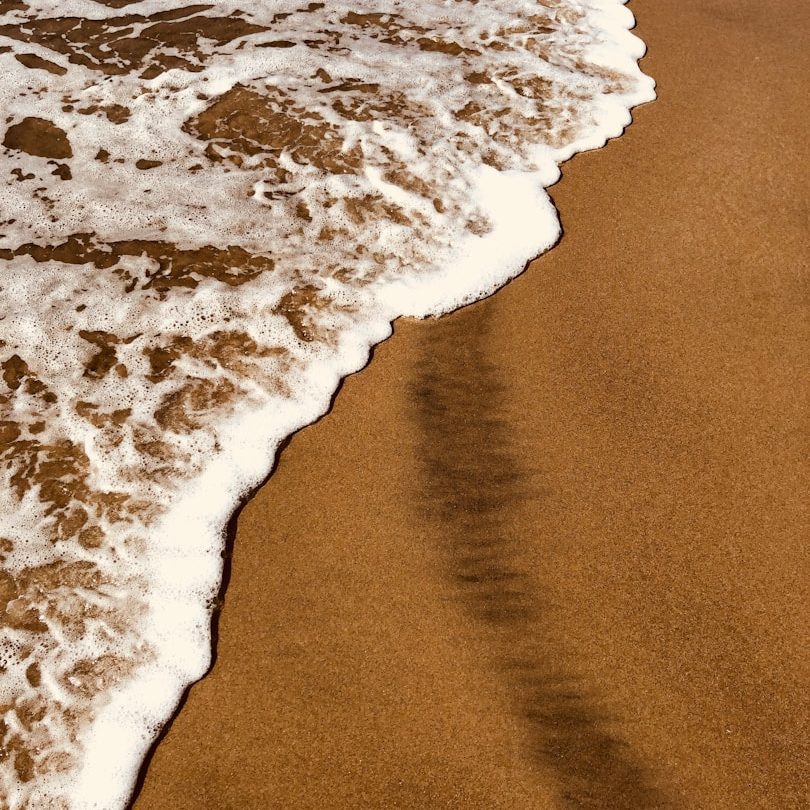 Schäumendes Wasser, das sanft den goldenen Sandstrand umspült.